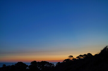Silhouette mit Bäumen und viel blauem Himmel kurz vor dem Sonnenaufgang als Hintergrundbild,