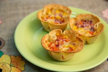 Baked pastry in the shape of a basket filled with cheese, tomatoes and corn