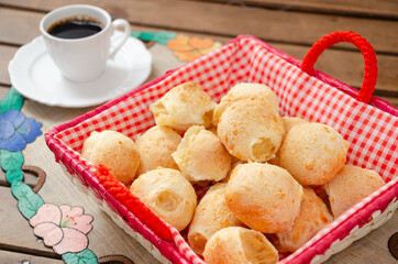 Brazilian cheese bread in a basket with coffee in background. Typical snack know as Pão de Queijo