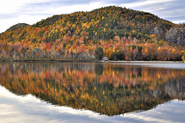 Late autumn afternoon in New Hampshire’s Franconia Notch State Park. Colorful fall foliage reflecting on calm surface of Echo Lake. Artists Bluff, with open ledges, at far top right.