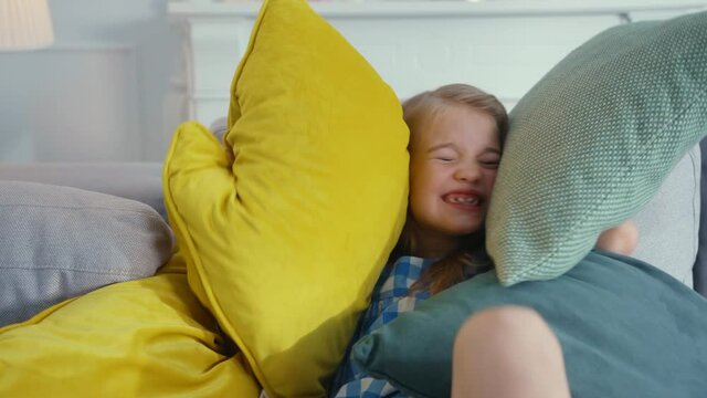 Adorable sweet young preschool girl child playing with pillows on bed sofa having fun in the living room. Happy childhood. Cute children. Portrait.