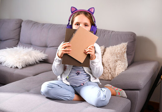 Little girl musical headphones got ready to go to school. Schoolgirl with a backpack, books for the school day. Education, learning concept. Happy child . Free space for text