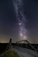 Fototapeta na wymiar The Milky Way Galaxy stretches across a night sky full of stars at Measle Road Bridge in rural Morgan County, Indiana.