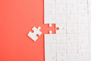 Top view flat lay of paper plain white jigsaw puzzle game texture last pieces for solve and place, studio shot on a red background, quiz calculation concept - obrazy, fototapety, plakaty