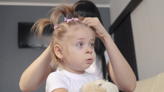 mom and daughter combing a hair makes hairstyle. happy family concept teamwork childcare. woman mother braids little girl. mom and daughter are lifestyle engaged in womens affairs
