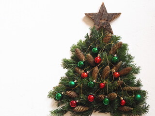 Christmas card.Christmas tree made of fir branches with a wooden star, Christmas tree cones and Christmas balls on a white background.