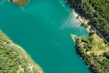 abandoned limestone quarry filled with turquoise water. lake surrounded with green forest. aerial photo