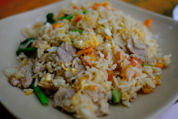 Fried rice with vegetables, broccoli, peas and eggs in a white bowl.