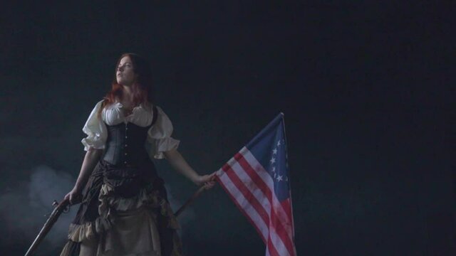 Young patriot girl in historical dress with pistol and flag. Historical concept from American Revolutionary War