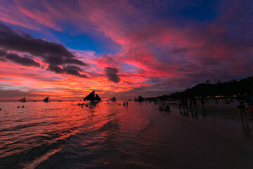 フィリピン・ボラカイ島のホワイトビーチから、海に太陽が沈む夕焼けの空を眺める