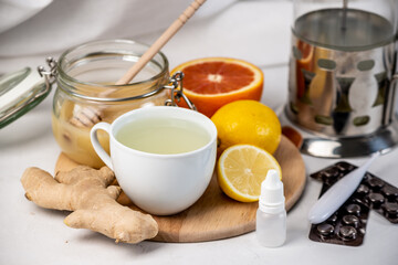 Hot tea with ginger, honey, lemon and preparations for cold and a thermometer. Concept of vitamin healthy tea for the sick