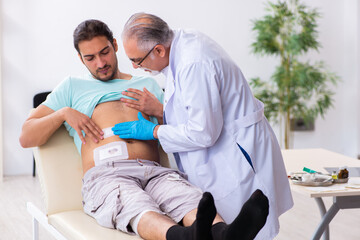 Injured young man visiting experienced male doctor