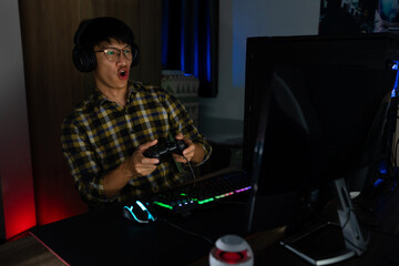 Involved asian man cyber sport gamer concentrated playing video games on computer at night dark room at home, eSport and technology concept © snowing12