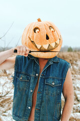 Halloween pumpkin brushes its big teeth with a knife