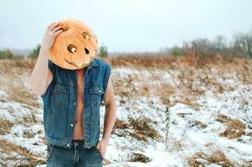 man in a denim jacket with a Halloween pumpkin on his head