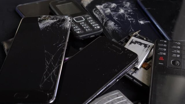 Obsolete and broken smartphones, used old cell phones, digital tablets, smart watches, with cracked screen. Household electronic waste recycle problem