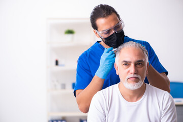 Old man visiting young male doctor in hair transplantation conce
