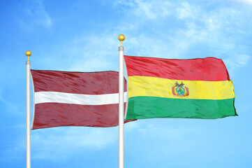 Latvia and Bolivia two flags on flagpoles and blue sky