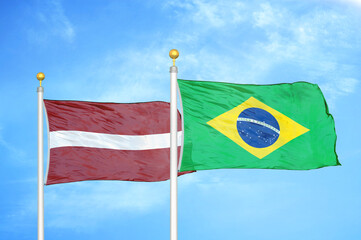 Latvia and Brazil two flags on flagpoles and blue sky