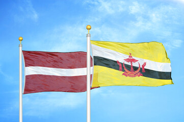 Latvia and Brunei two flags on flagpoles and blue sky