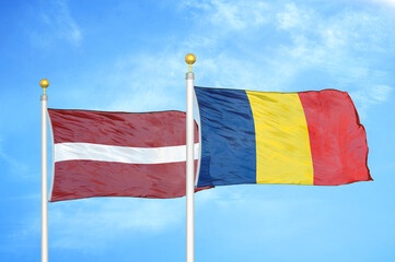 Latvia and Chad two flags on flagpoles and blue sky