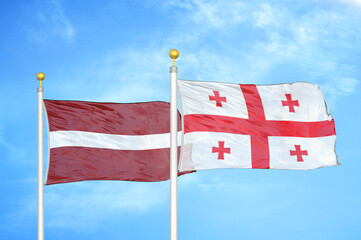 Latvia and Georgia two flags on flagpoles and blue sky