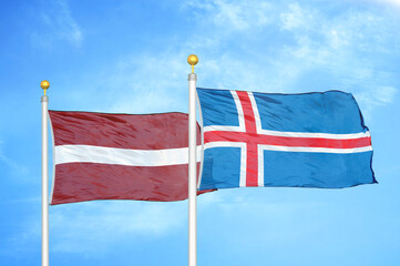 Latvia and Iceland two flags on flagpoles and blue sky