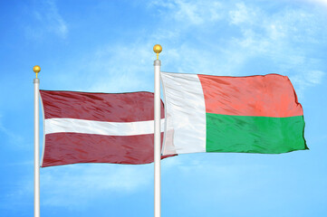 Latvia and Madagascar two flags on flagpoles and blue sky