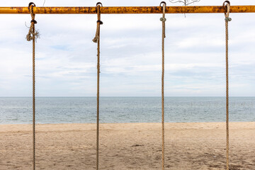 Seascape shot at a peaceful and clean beach under blue cloudy sky with local swing ropes as foreground