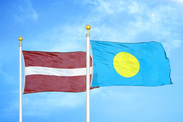 Latvia and Palau two flags on flagpoles and blue sky