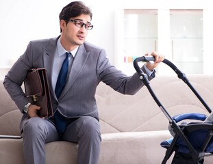 Businessman looking after newborn baby at home and teleworking
