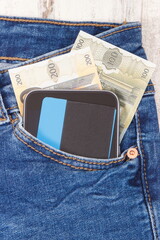Credit card, money and mobile phone in jeans pocket. Cashless or cash paying for shopping concept