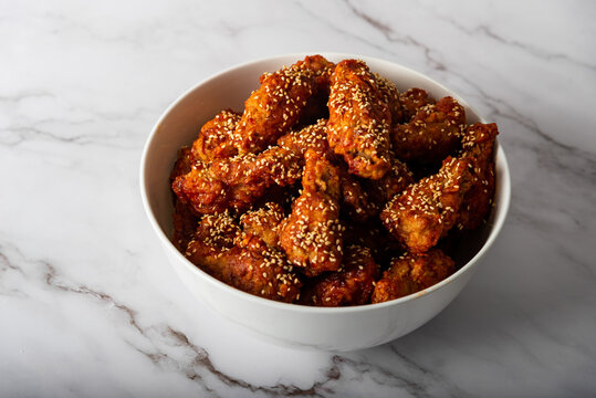 Korean fried chicken with sesame grain topping and marinated with gochujang chili paste 

