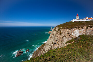 A wide angle image of the famous cabo da roca (Cape Roca) the promontory that marks the westernmost point in continental Europe. Photo features steep cliffs, granite boulders, a clifftop lighthouse.