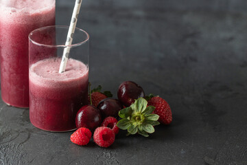 Berries smoothie made with blended cherry, strawberry and raspberry in glass on dark concrete background. Delicious fruit drink  for health and detox