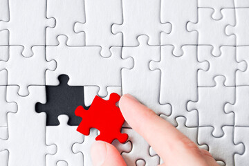 White gray puzzles are stacked on black background. One piece, colored red, located separately. Not...