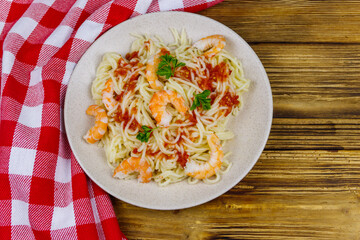 Spaghetti pasta with prawns, tomato sauce and parsley on wooden table. Top view