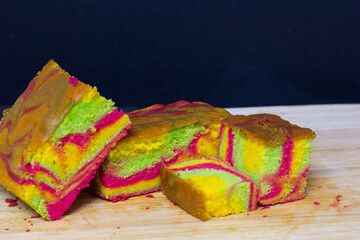 Rainbow marble butter cake with green, yellow and cochineal red food coloring on wooden board