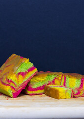 Rainbow marble butter cake with green, yellow and cochineal red food coloring on wooden board