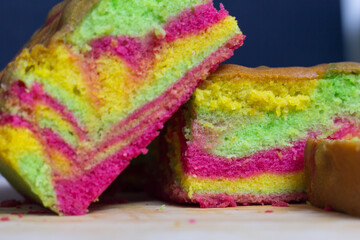 Rainbow marble butter cake with green, yellow and cochineal red food coloring on wooden board in a closeup shot