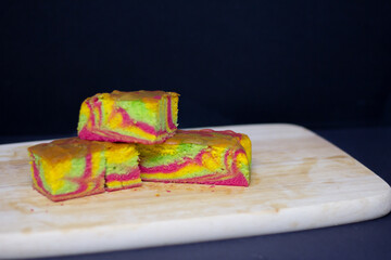 Rainbow marble butter cake with green, yellow and cochineal red food coloring on wooden board