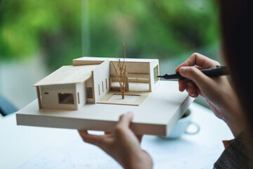An architect holding and working on an architecture house model with shop drawing paper in the...