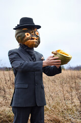 man in a fancy dress is celebrating Halloween and showing a cut up ripe pumpkin