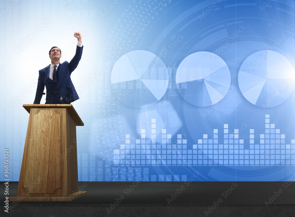 Wall mural Man businessman making speech at rostrum in business concept