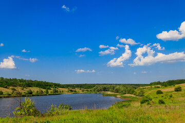 Fototapeta na wymiar Summer landscape with beautiful lake, green meadows, hills, trees and blue sky