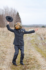 man in fancy dress celebrates Halloween and waves a hat on a rural dirt road