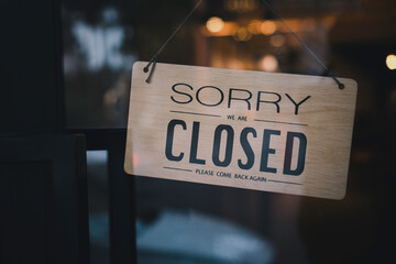 The sign is closed. Hanging on the glass at the front door, the sign message on a wooden, please...