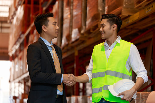 factory worker team hands shaking greeting start up plan new project warehouse behind white safety helmet on workplace walking talking at warehouse site, partnership, contractor concept.