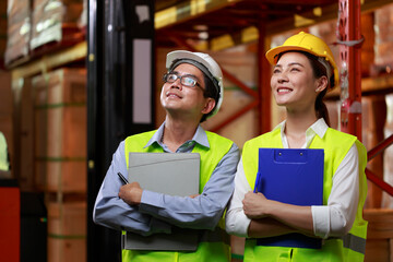 looking up confident beyond business industry concept, Asian worker holding clipboard standing shin up happy smiley face with safety hard hat, warehouse factory business concept.
