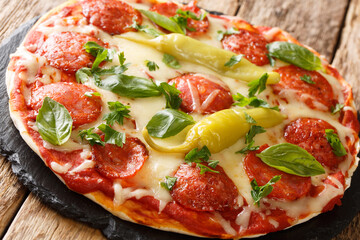 Spicy chorizo pizza with chili, mozzarella, tomatoes and herbs close-up on a board on the table. horizontal